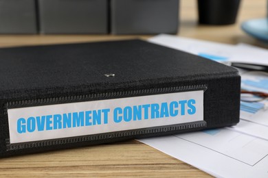 Image of Black folder with Government Contracts label on desk in office, closeup