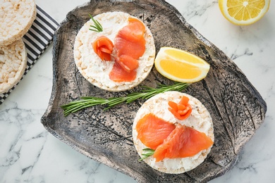 Plate of crispbreads with fresh sliced salmon fillet on table, top view