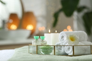 Composition with different spa products and burning candles on table indoors. Space for text