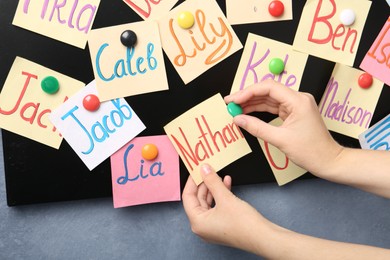 Photo of Woman putting notes with baby names on board, closeup