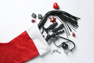 Photo of Christmas stocking with different sex toys on white background, top view