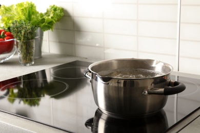 Photo of Pot with boiling water on electric stove in kitchen, space for text