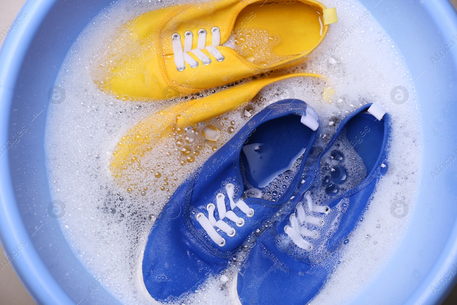 Photo of Washing sport shoes in plastic basin, top view