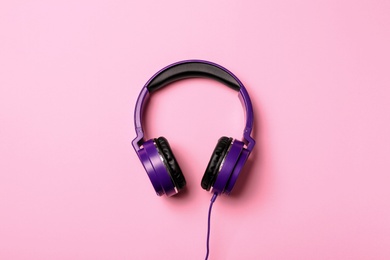 Photo of Stylish modern headphones on color background, top view