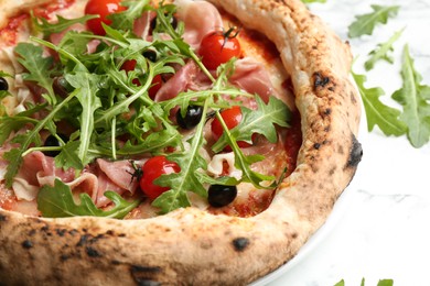 Photo of Tasty pizza with meat and arugula on white table, closeup