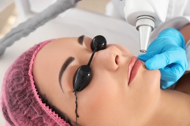 Photo of Woman undergoing laser tattoo removal procedure in salon, closeup