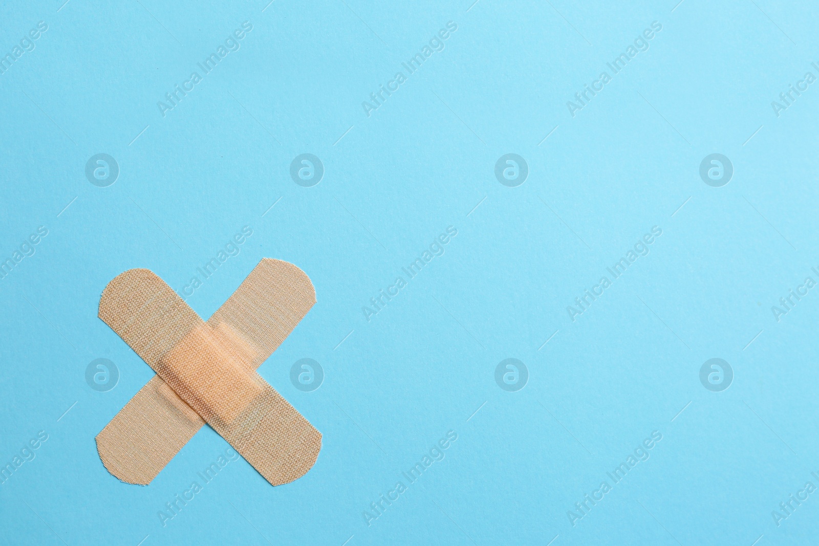 Photo of Sticking plasters on light blue background, top view. Space for text