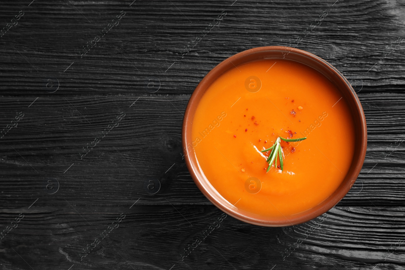 Photo of Bowl of tasty sweet potato soup on wooden table, top view. Space for text