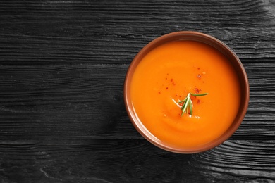 Bowl of tasty sweet potato soup on wooden table, top view. Space for text