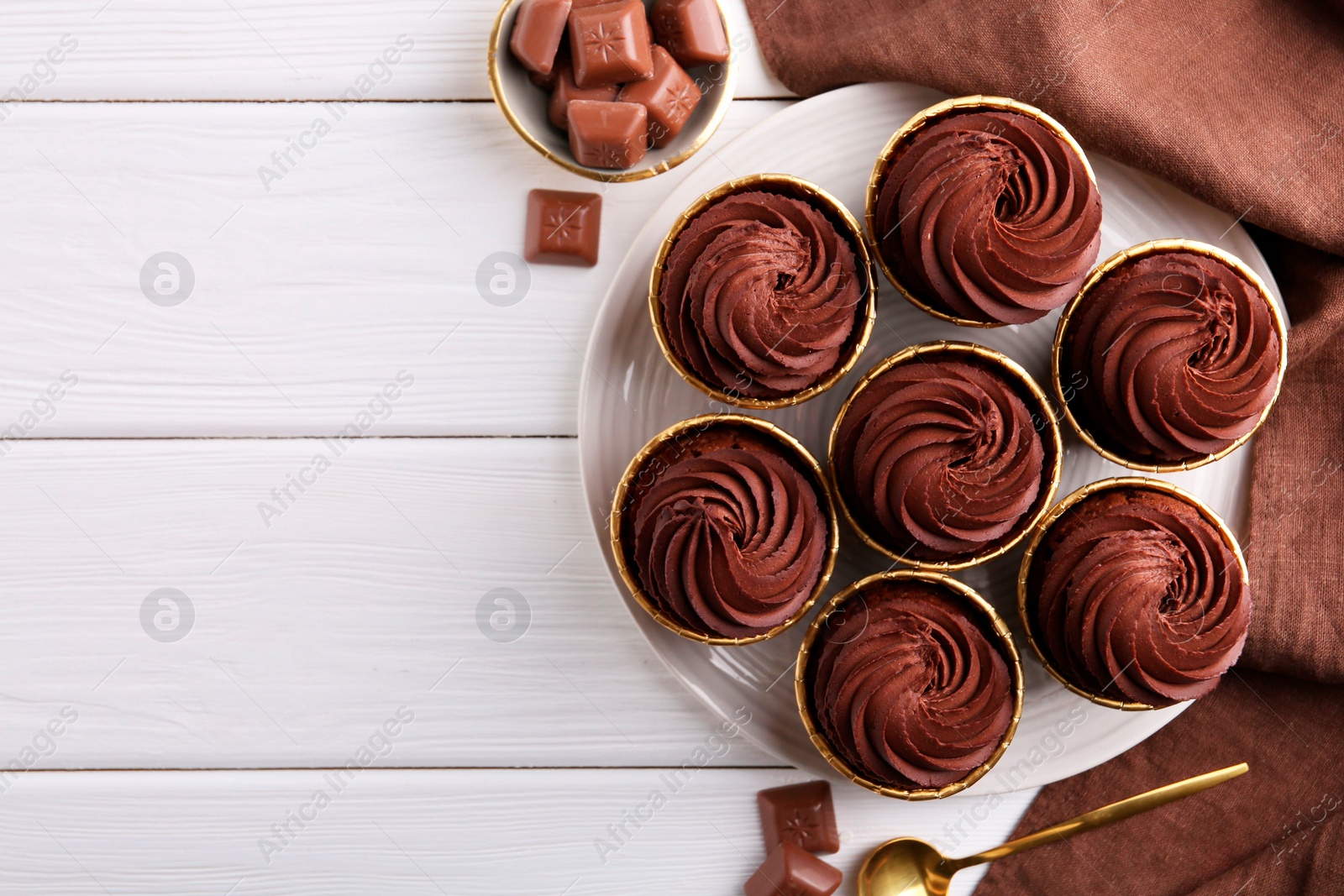 Photo of Delicious cupcake and chocolate pieces on white wooden table, flat lay. Space for text