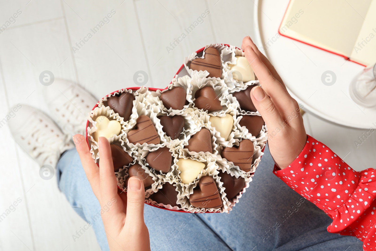 Photo of Woman with box of heart shaped chocolate candies indoors, closeup