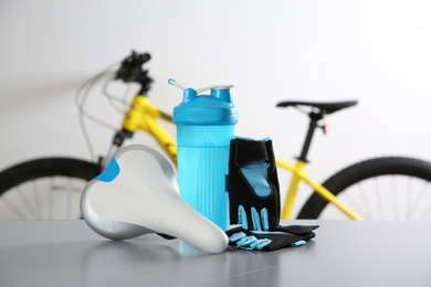 Bicycle saddle, bottle and gloves on grey table