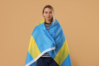 Photo of Happy woman with flag of Sweden on beige background