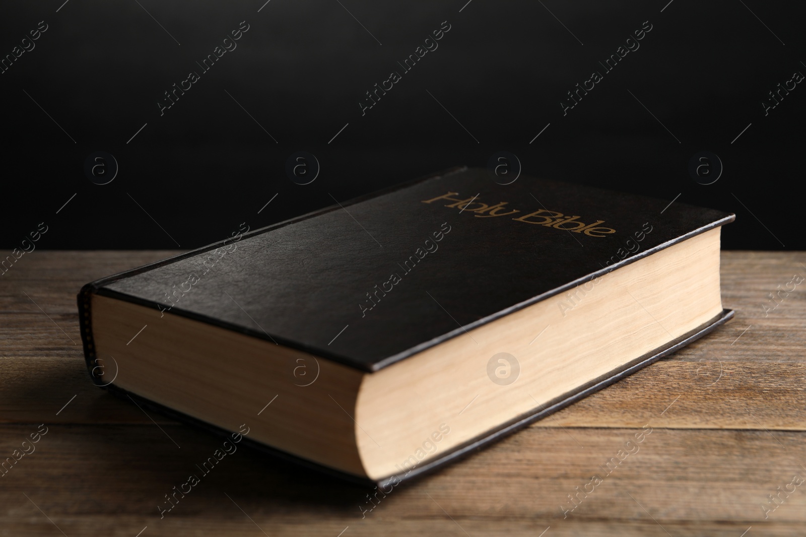 Photo of Bible with dark cover on wooden table. Christian religious book