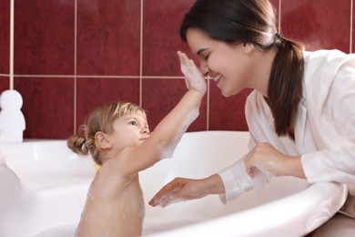 Photo of Happy mother with her little daughter spending time together in bathroom