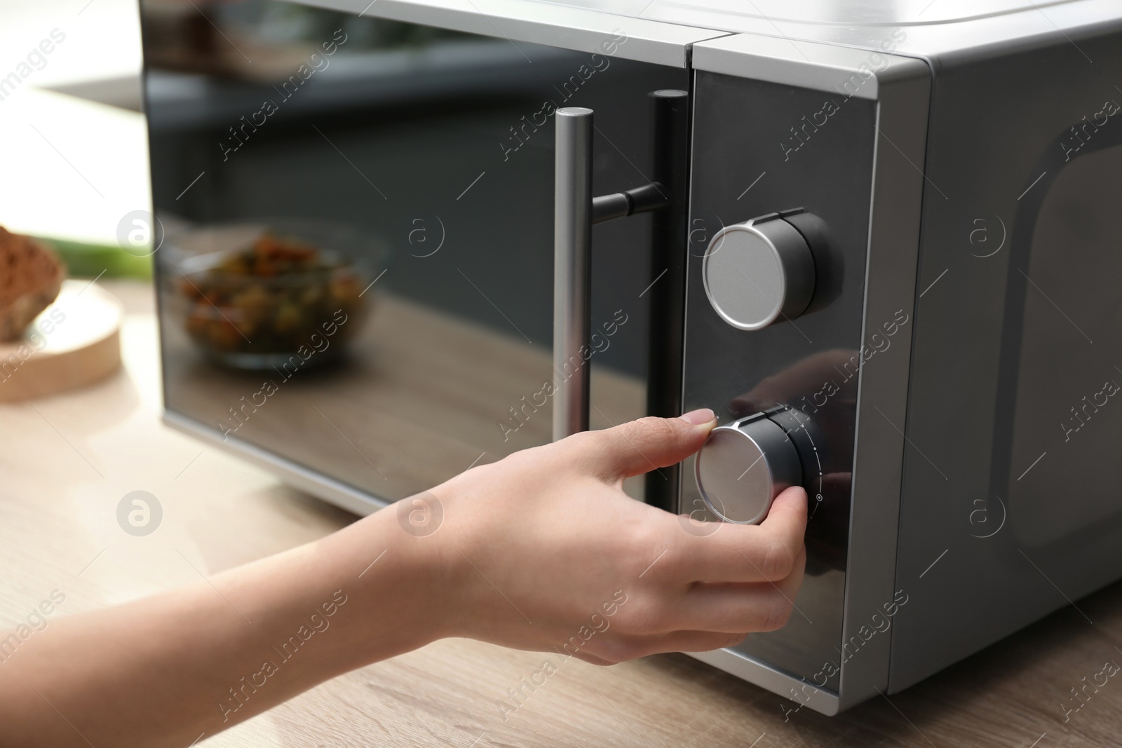 Photo of Young woman adjusting modern microwave oven in kitchen, closeup