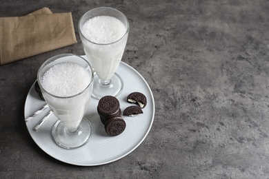 Photo of Glasses of milk with chocolate cookies on grey background, space for text