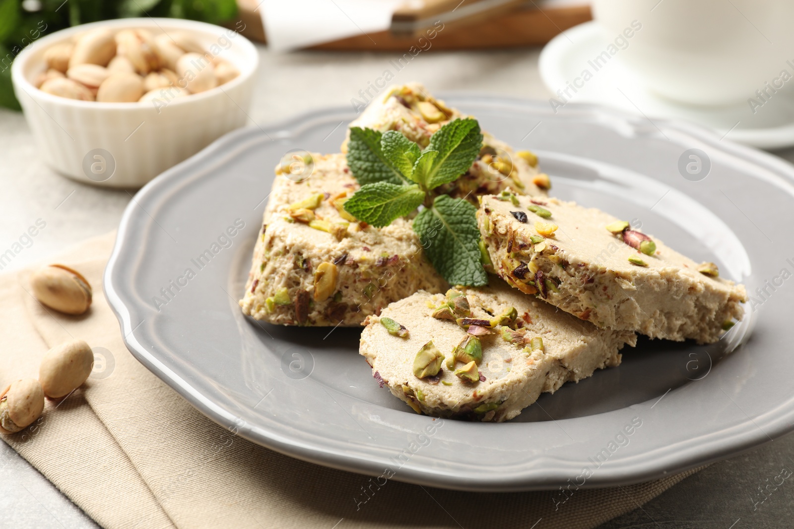 Photo of Tasty halva with pistachios and mint on table, closeup