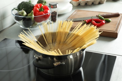 Photo of Cooking spaghetti in pot on electric stove