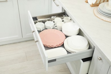 Photo of Clean plates, bowls and cups in drawer indoors