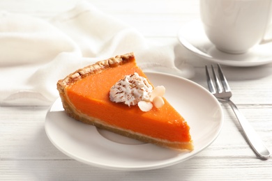 Plate with piece of fresh delicious homemade pumpkin pie on wooden table