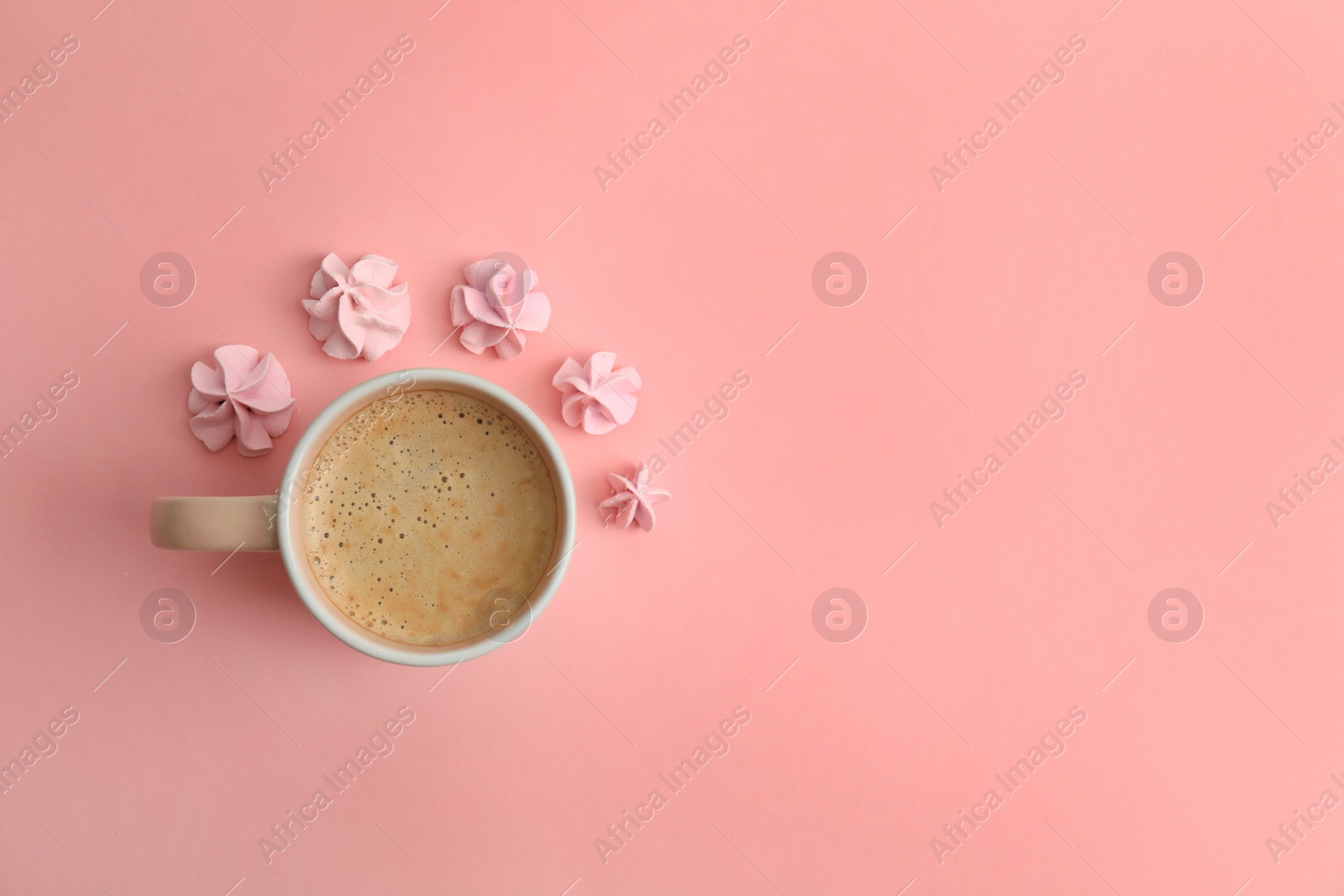 Photo of Cup of coffee and meringues on pink background, top view. Space for text