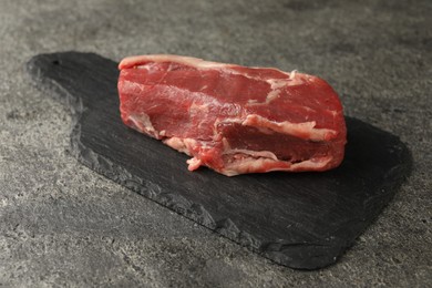 Photo of Piece of raw beef meat on grey textured table