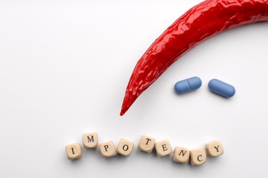 Photo of Chili pepper, pills and cubes with word Impotency on white background, flat lay. Space for text