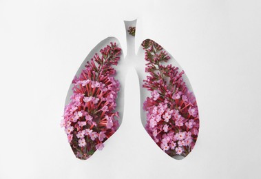 Human lungs shape hole in white paper with beautiful flowers, top view
