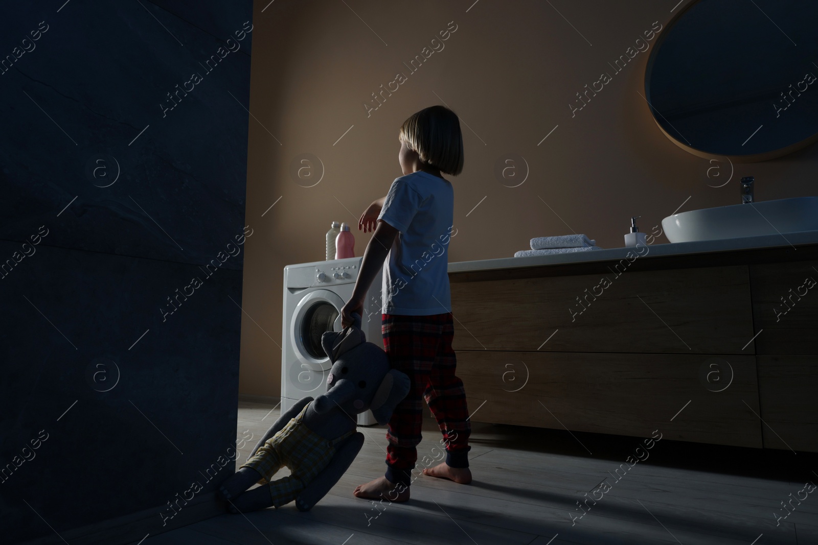 Photo of Boy in pajamas with toy elephant sleepwalking indoors at night