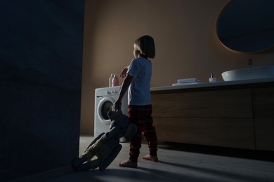 Photo of Boy in pajamas with toy elephant sleepwalking indoors at night
