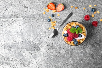 Photo of Glass of healthy homemade granola dessert on grey table, flat lay. Space for text