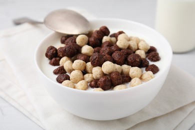 Photo of Breakfast cereal. Tasty corn balls with milk in bowl and spoon on table, closeup