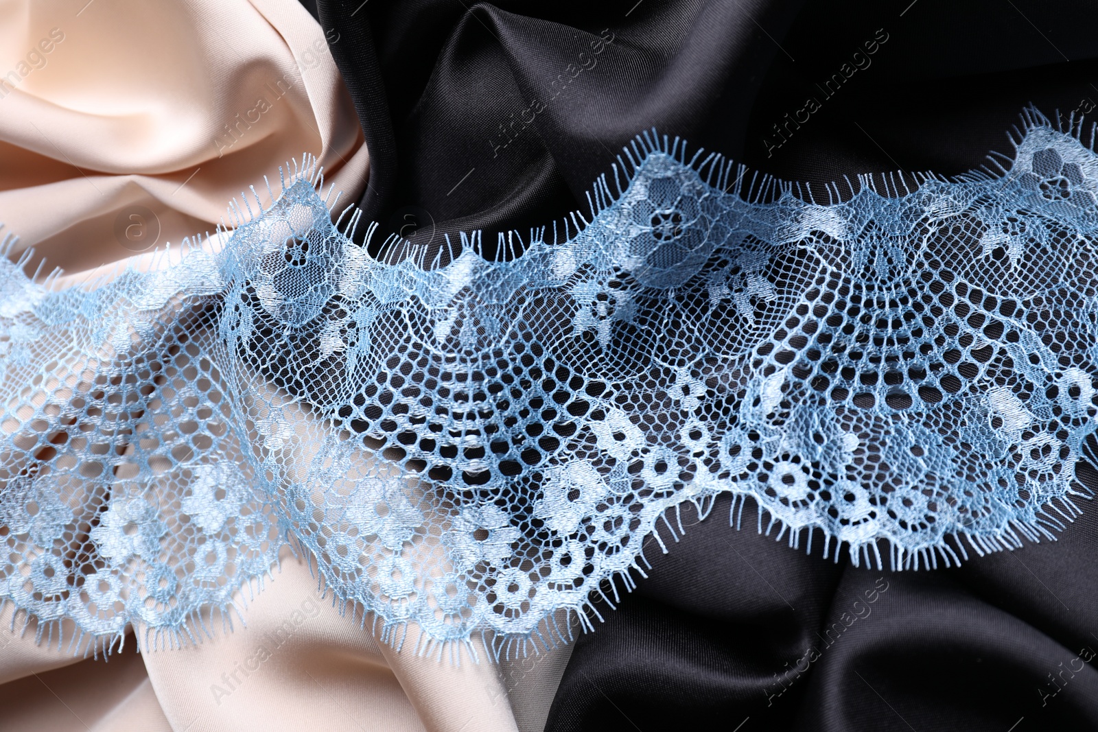 Photo of Beautiful light blue lace on color fabrics, top view