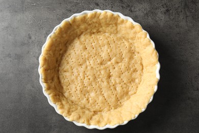 Photo of Making shortcrust pastry. Raw dough in baking dish on grey table, top view
