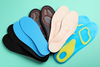 Photo of Pairs of different shoe insoles on turquoise background, flat lay