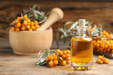 Natural sea buckthorn oil and fresh berries on wooden table. Space for text