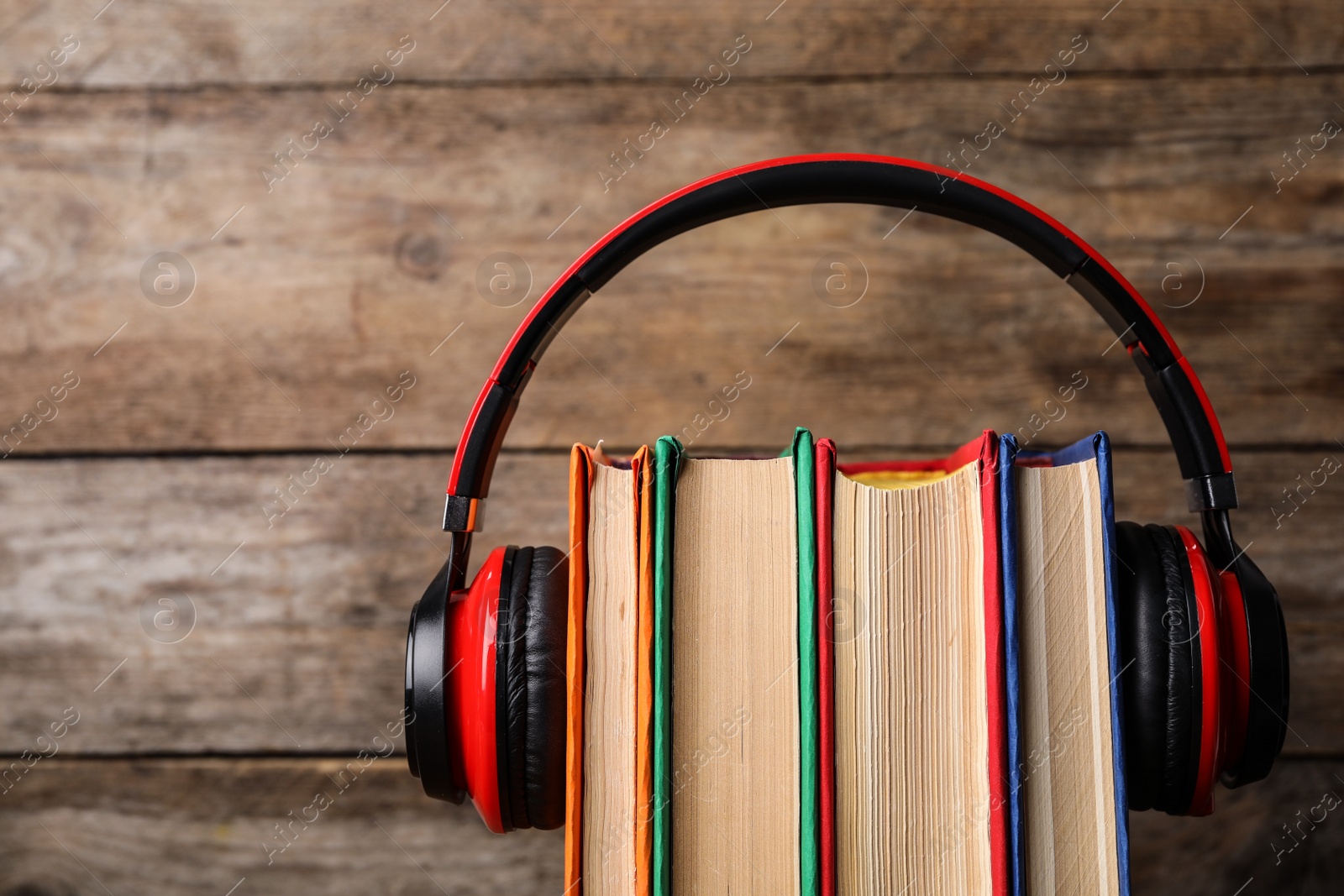 Photo of Books and modern headphones on wooden background, closeup