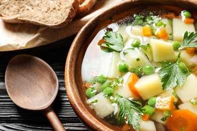 Photo of Bowl of fresh homemade vegetable soup served on wooden table, closeup