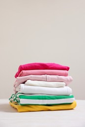 Photo of Stack of folded clothes on table against beige background
