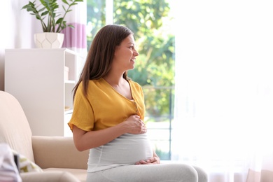 Pregnant woman sitting on sofa at home