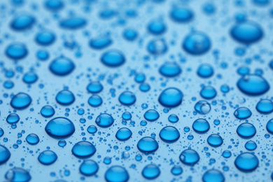 Photo of Water drops on blue background, closeup view