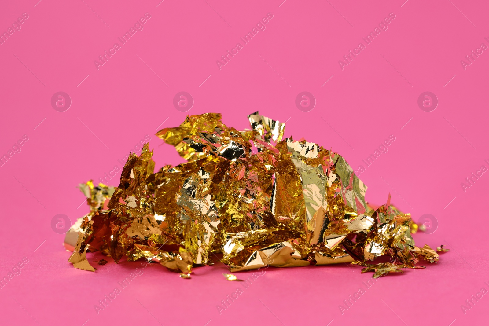 Photo of Pieces of edible gold leaf on pink background, closeup