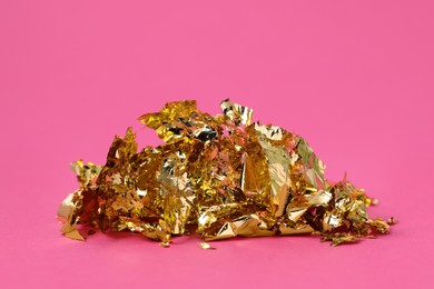 Photo of Pieces of edible gold leaf on pink background, closeup