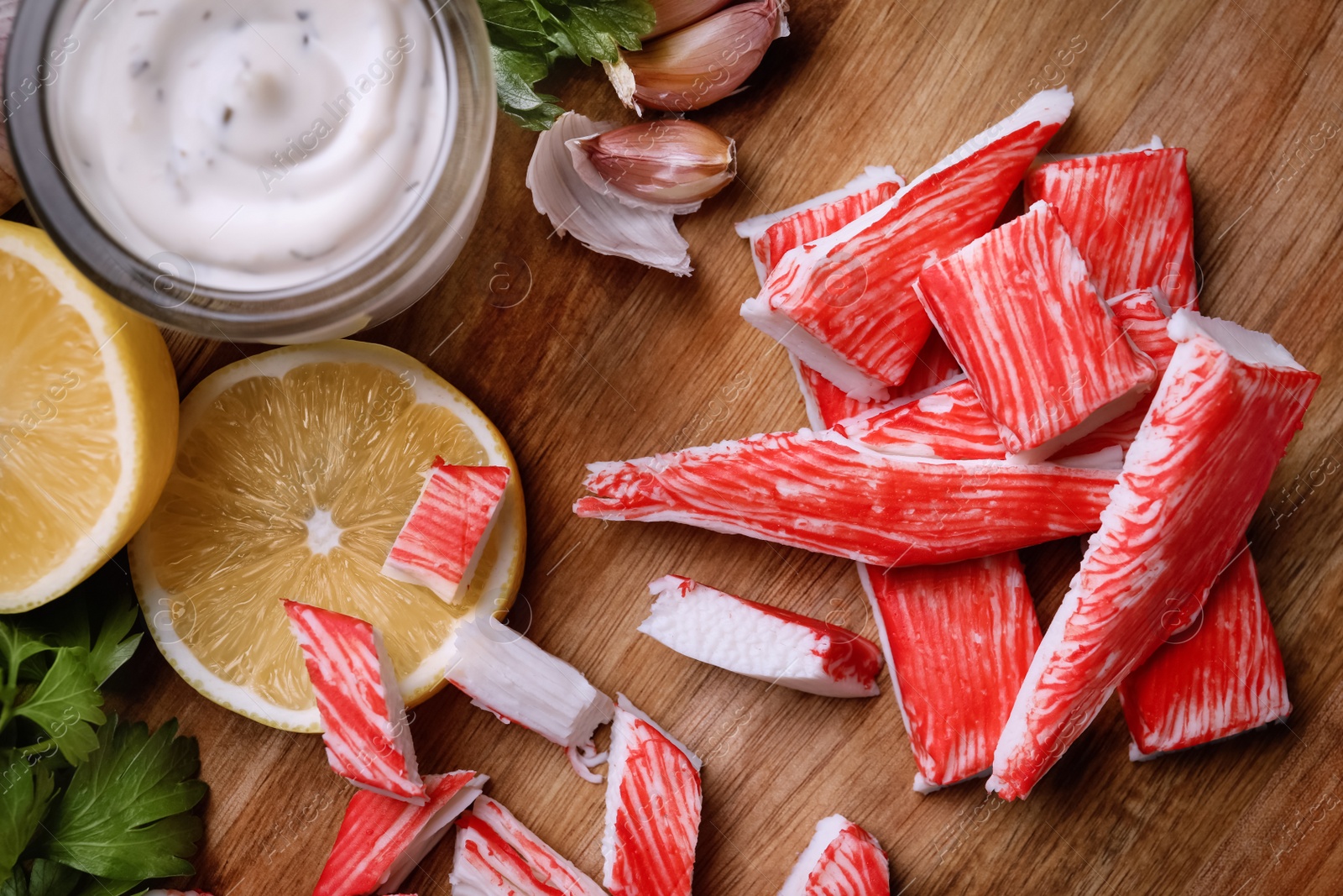 Photo of Delicious crab sticks served on wooden board, flat lay