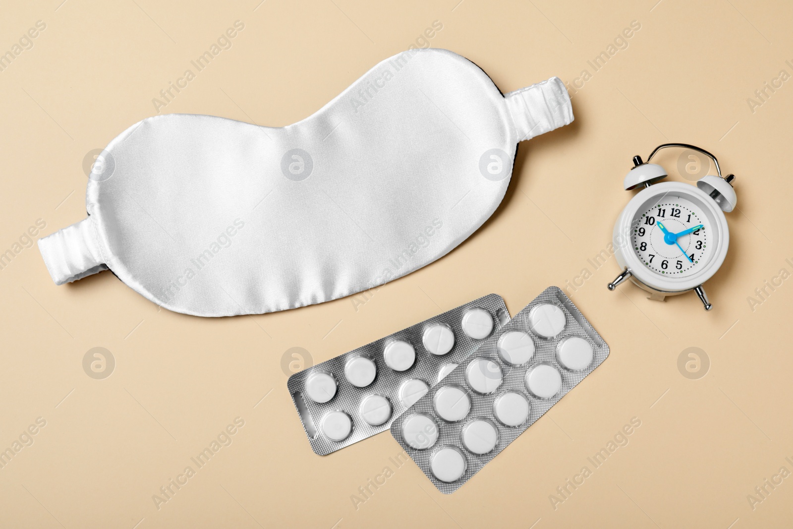 Photo of Sleeping mask, pills and alarm clock on yellow background, flat lay. Bedtime accessories