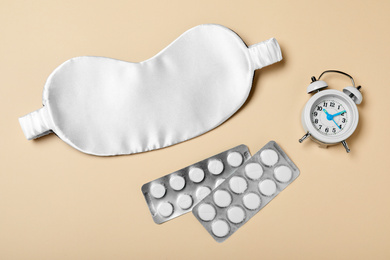 Photo of Sleeping mask, pills and alarm clock on yellow background, flat lay. Bedtime accessories