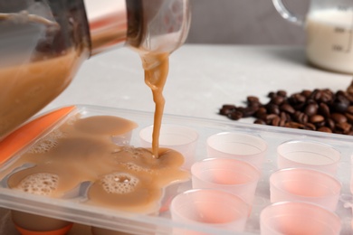 Pouring coffee drink into ice cube tray on table, closeup