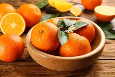 Delicious ripe oranges on wooden table, closeup