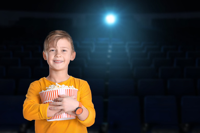 Image of Cute boy with popcorn bucket in cinema, space for text